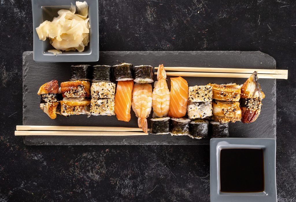 Sushi plate on dark stone next to chopsticks on black background in studio. Healthy asian food